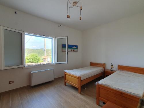 Un dormitorio con dos camas y una gran ventana. en Villetta Muntelgu, en Castelsardo