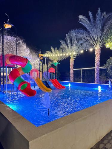 a childrens pool at night with a water park at استراحة الخيالة in Falaj al Mu‘allá