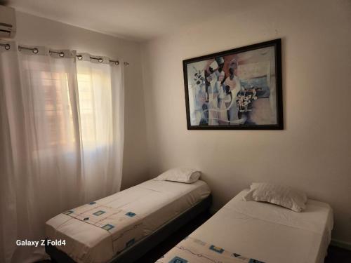 two beds in a room with a picture on the wall at Appartement Sao Filipe in Praia