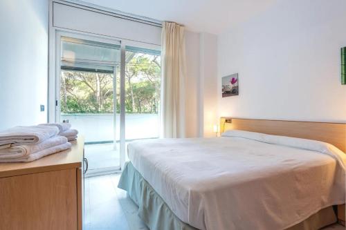 um quarto com uma cama e uma grande janela em Apartamento en S'Abanell Central Park em Blanes