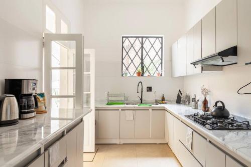 a white kitchen with white cabinets and a sink at UCO Live Roma in Mexico City