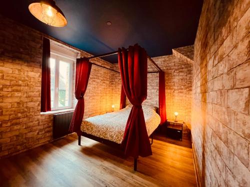 - une chambre avec un lit doté de rideaux rouges dans l'établissement Le Logis Des Sorciers, à Montluçon