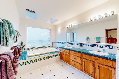 uma casa de banho com 2 lavatórios, uma banheira e uma janela em Pebble Beach Bliss em Crescent City