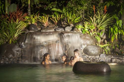 a group of people in the water near a waterfall at Hotel Arenal Springs Resort & Spa in Fortuna