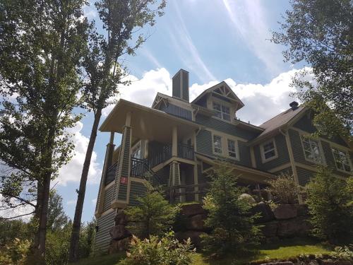 a large green house with trees in front of it at Tremblant Prestige - Les Eaux 227-3 in Mont-Tremblant