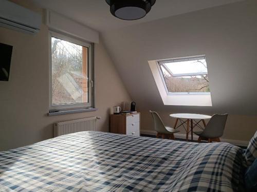 ein Schlafzimmer mit einem Bett, einem Tisch und zwei Fenstern in der Unterkunft La Fontaine Aux Enfants - Chambre avec sdb privée in Abreschviller
