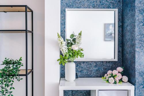 a vase of flowers on a table with a mirror at The Retreat near Salford Quays in Manchester