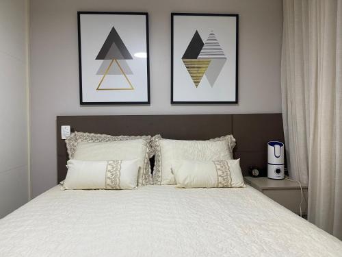 a bedroom with a bed with four pictures on the wall at Apartamento em Nova Aliança in Ribeirão Preto