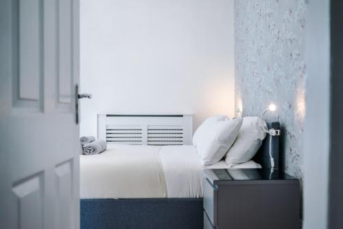 a bedroom with a bed with white sheets and pillows at The Retreat near Salford Quays in Manchester