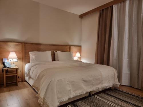 a bedroom with a large white bed with two lamps at Likoria Hotel in Arachova