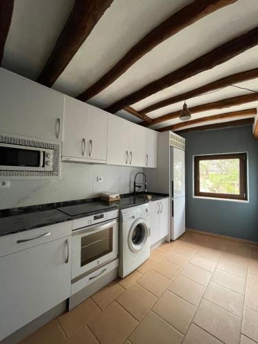 a kitchen with white cabinets and a washer and dryer at Hotel Boutique Malanquilla Inedita in Malanquilla