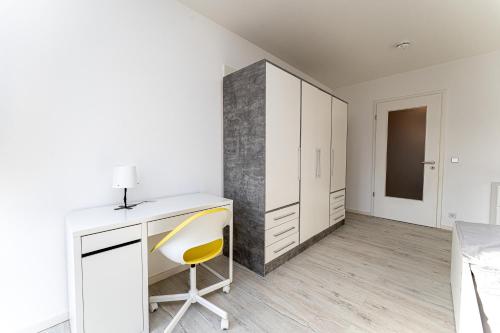 Habitación blanca con escritorio y silla amarilla en Grand Appartement nahe Müggelsee en Berlín