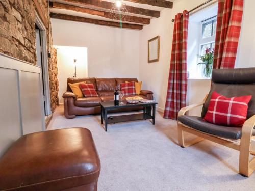 a living room with a leather couch and a table at The Brewhouse in Church Stretton