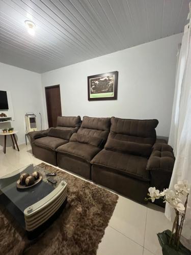een woonkamer met een bruine bank en een tafel bij POUSADA CABANA DO PARQUE in Mateiros