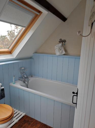 une baignoire dans une salle de bain avec une fenêtre dans l'établissement Cottage Breton, à Les Champs-Géraux