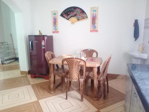 a kitchen with a table and chairs and a refrigerator at Areca Holiday Apartment in Siliguri