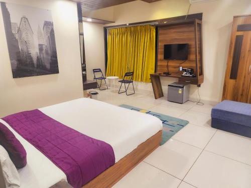 a bedroom with a bed and a desk and a television at Passiflora Beach Resort Alibaug in Alibaug