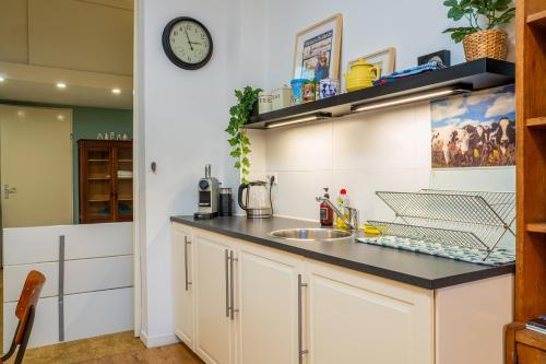 a kitchen with a sink and a clock on the wall at Stylish Private Studio Close to City in Amsterdam