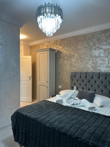 a bedroom with a large black bed with a chandelier at Apartament Simoni in Ploieşti