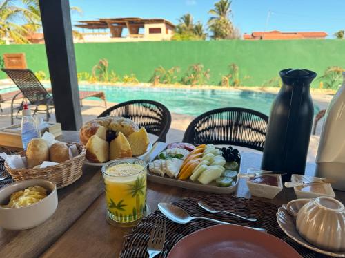 a table with breakfast foods and drinks and a pool at Pousada Lá em Casa in Barra Grande