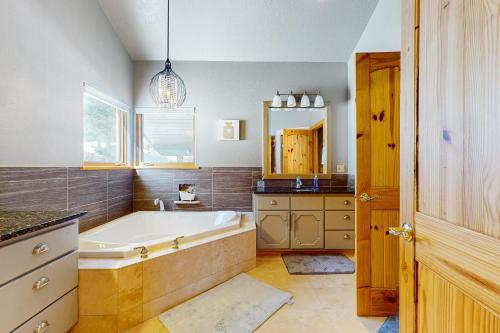 a bathroom with a tub and a sink and a mirror at Le Chalet Bleu in Angel Fire