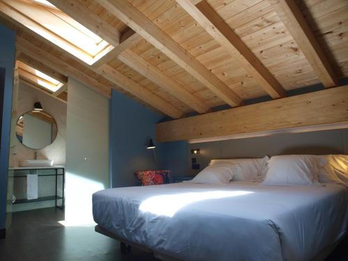 a bedroom with a large bed with a wooden ceiling at M&UGA Hotela in Elorrio