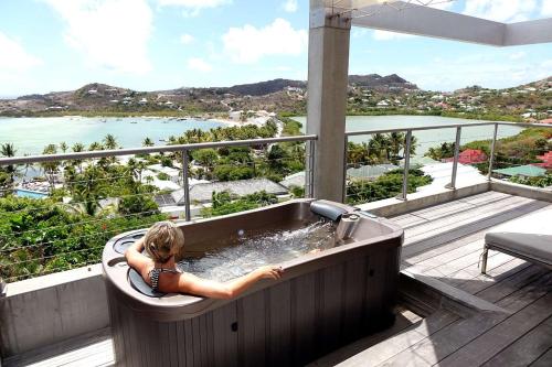 a woman sitting in a bath tub on a balcony at Villa Lodge 4 Epices in Gustavia