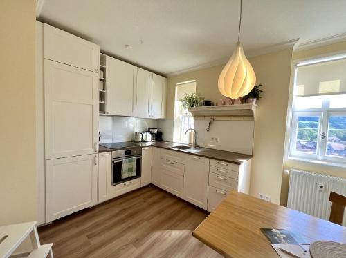 uma cozinha com armários brancos e uma mesa de madeira em Wohlfühl-Apartment in historischer Burg nahe Fulda em Schlitz