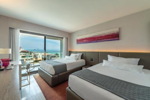 a hotel room with two beds and a balcony at Lifestyle Laghetto Collection in Rio de Janeiro