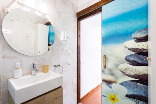 La salle de bains est pourvue d'un lavabo, d'un miroir et d'une pile de rochers. dans l'établissement EK El Risco Candelaria, à Candelaria