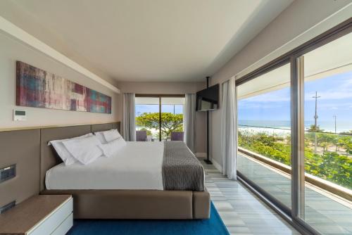a bedroom with a bed and a view of the ocean at Lifestyle Laghetto Collection in Rio de Janeiro