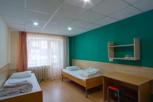a room with two beds and a desk and a green wall at Podolski Hostel in Kyiv