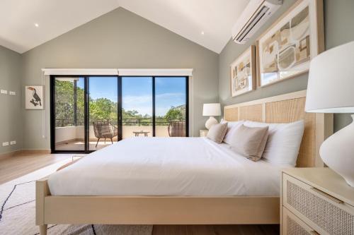 - une chambre avec un grand lit blanc et un balcon dans l'établissement Casa Camino, à Playa Grande