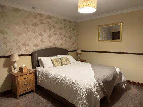 a bedroom with a bed and a nightstand with a white bedspread at The George at Donyatt in Ilminster