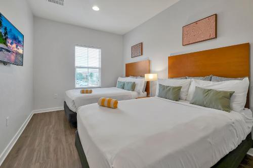 Regal Oaks Resort Vacation Townhomes by IDILIQ في أورلاندو: سريرين في غرفة بجدران بيضاء