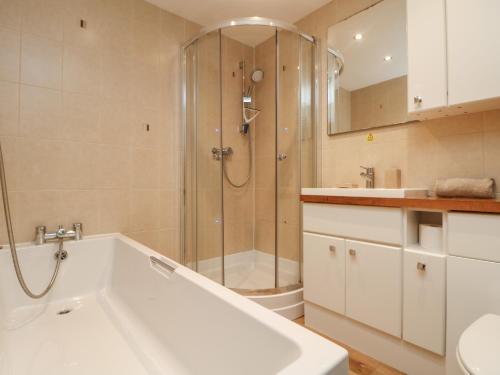 a bathroom with a tub and a shower and a sink at Ocean Blue in Porthtowan