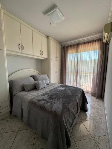 um quarto com uma cama e uma grande janela em Duplex Ametista em Gravatal