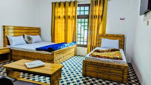 um quarto com duas camas e uma mesa em Relax hotel em Kalām