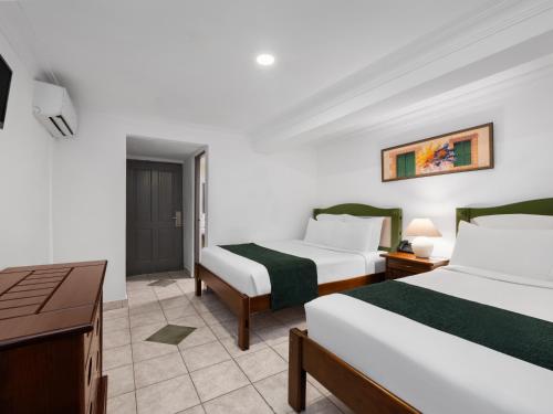 a hotel room with two beds and a desk at Gran Hotel Europa Santo Domingo Trademark Collection by Wyndham in Santo Domingo