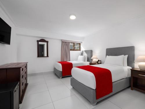 a hotel room with two beds and a television at Gran Hotel Europa Santo Domingo Trademark Collection by Wyndham in Santo Domingo