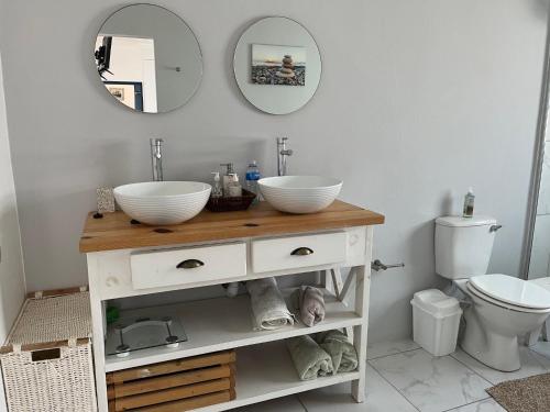 a bathroom with two sinks and two bowls on a counter at Kidds Beach Cottage in Kiddʼs Beach