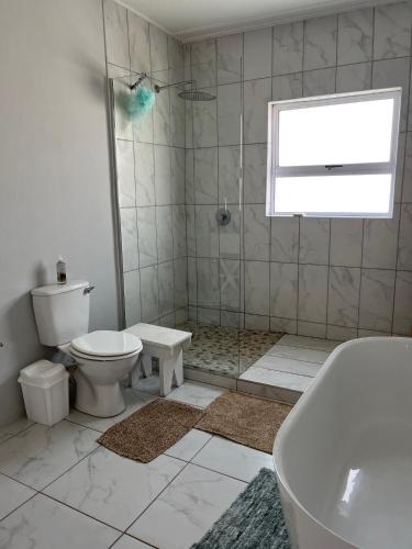 a bathroom with a toilet and a tub and a sink at Kidds Beach Cottage in Kiddʼs Beach