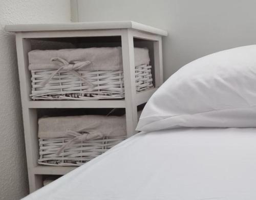 een witte plank met handdoeken en manden naast een bed bij Coqueto Apartamento en la Playa in Daimús