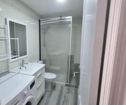 y baño blanco con ducha y aseo. en Coqueto Apartamento en la Playa, en Daimuz