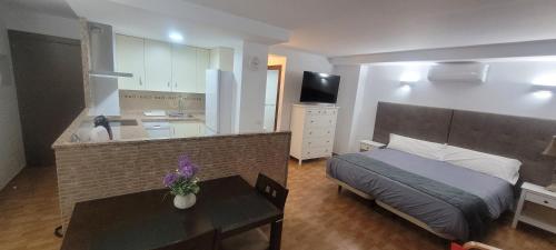 a bedroom with a bed and a table and a kitchen at Apartamentos luna in Ardales