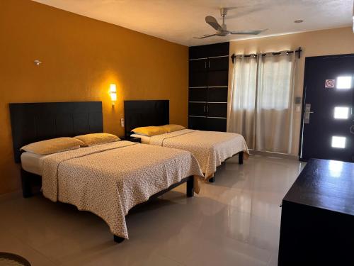 two beds in a room with yellow walls at Hotel Avila in Valladolid