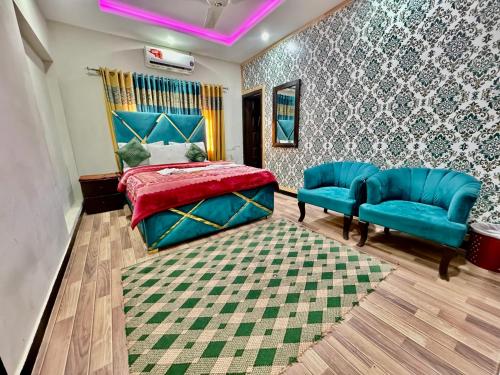 a bedroom with a bed and two blue chairs at Al Atif Guest House in Islamabad