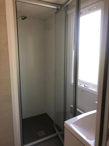 une salle de bain avec une douche, un lavabo et un miroir dans l'établissement Mobil-home Ouistreham, à Ouistreham