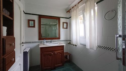 baño con lavabo, espejo y ventana en Casa la palmera, en Gormazo