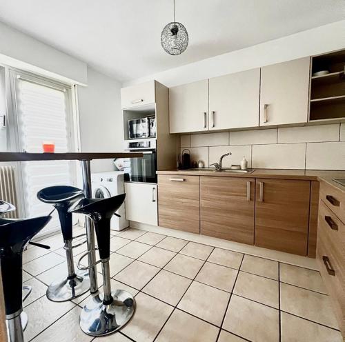 eine Küche mit einer Theke und einigen Hockern in der Unterkunft Appartement Illzach, 5 personnes in Illzach